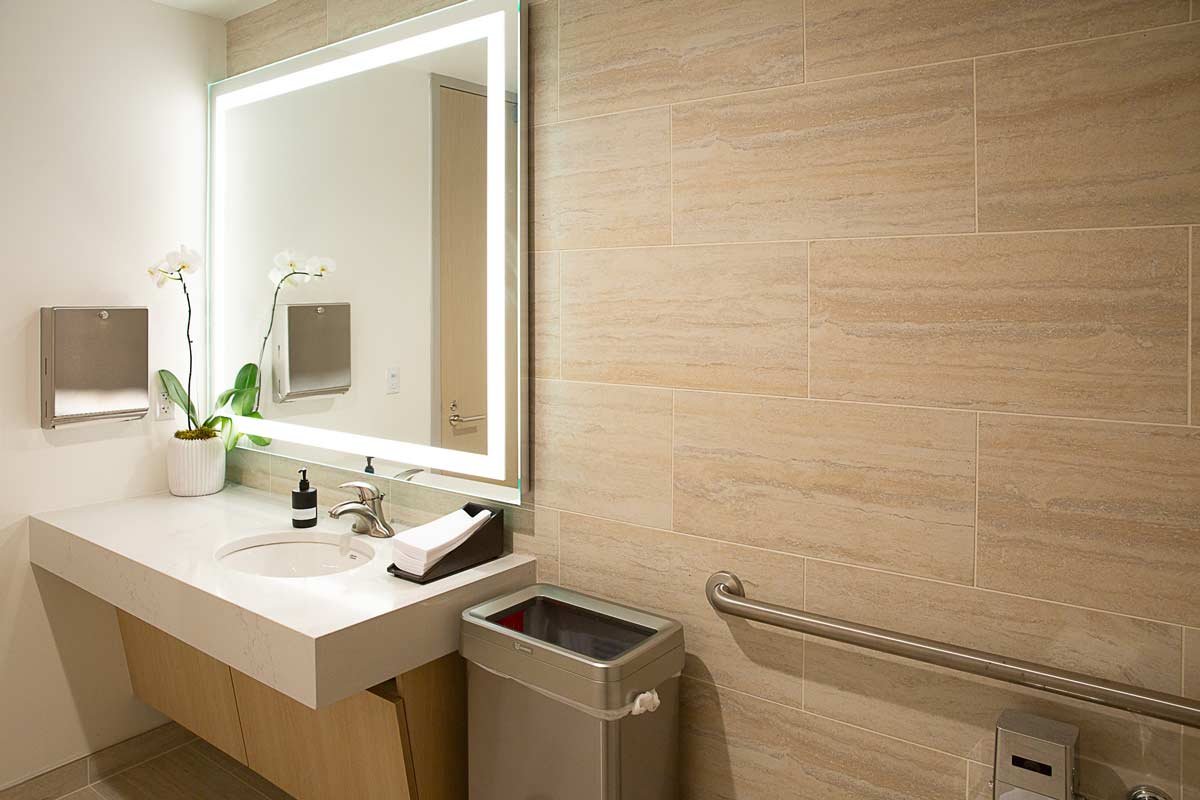 Tan colored bathroom wall with light colored sink and large mirrow