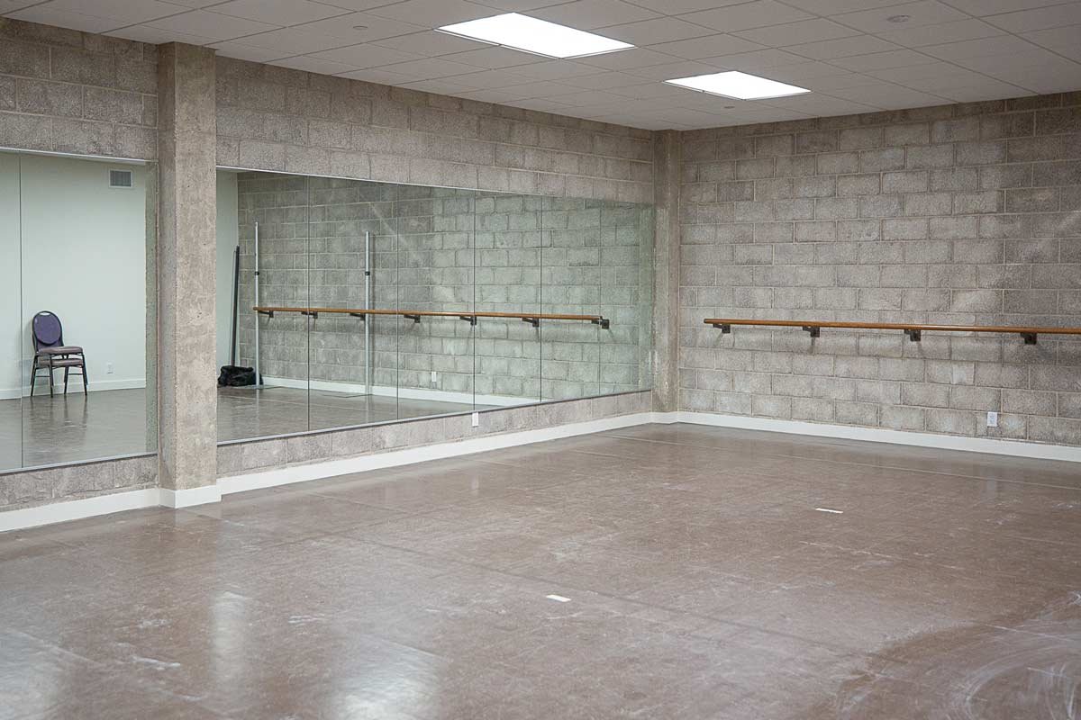 Rehearsal area with mirrored wall and ballet bar on wall
