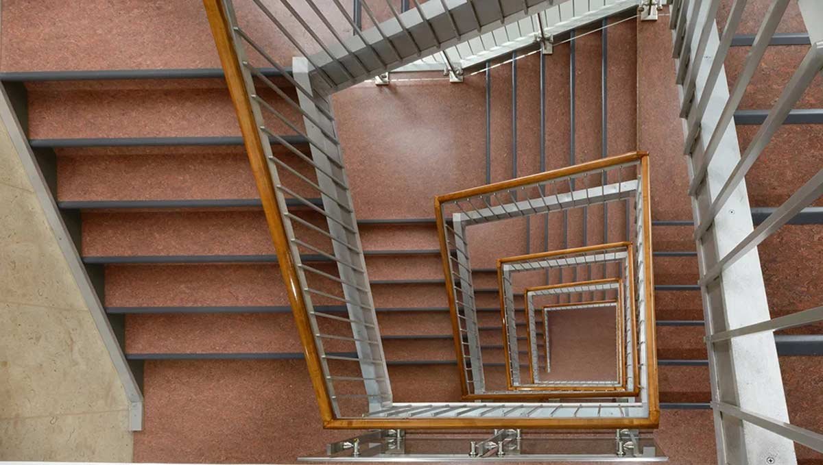 Looking down square stairwell at wrap around stair rails