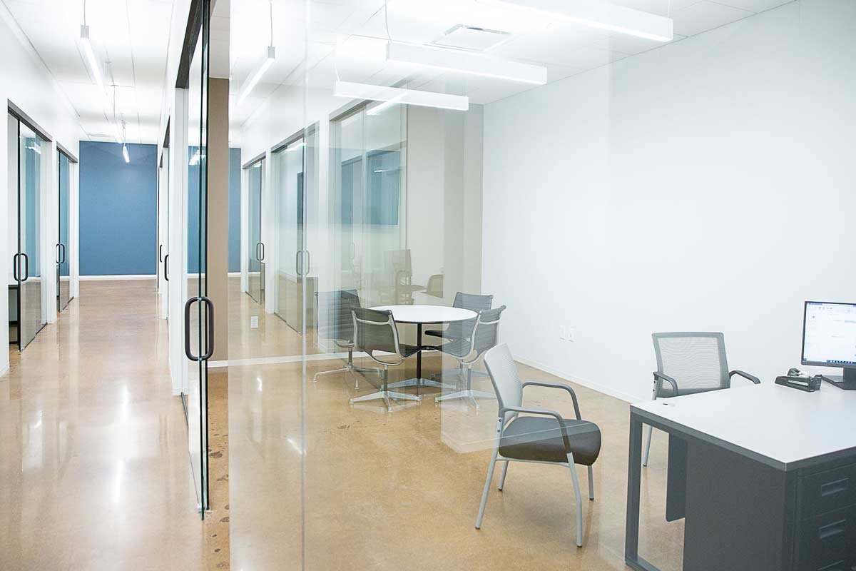 Office with desk and table seen through glass wall in the hallway