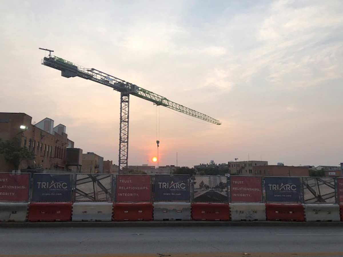 Construction area at dawn with crane and TriArc banner fence