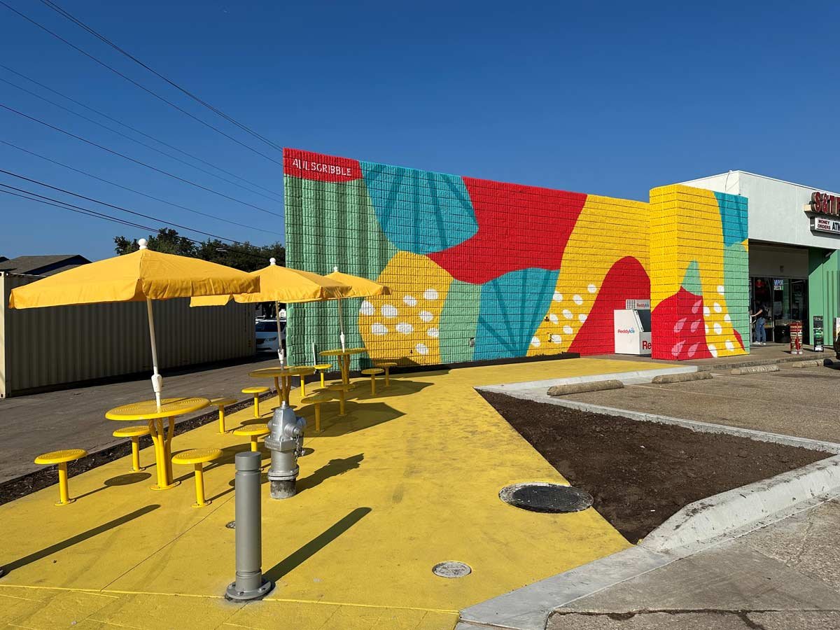 Colorful wall mural and picnic tables next to parking lot