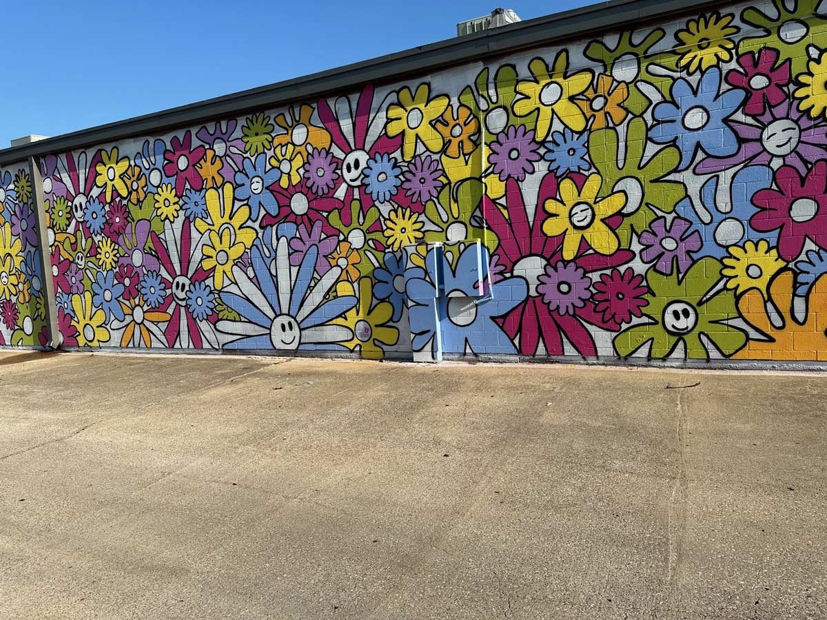 Colorful flower mural on the side of brick building