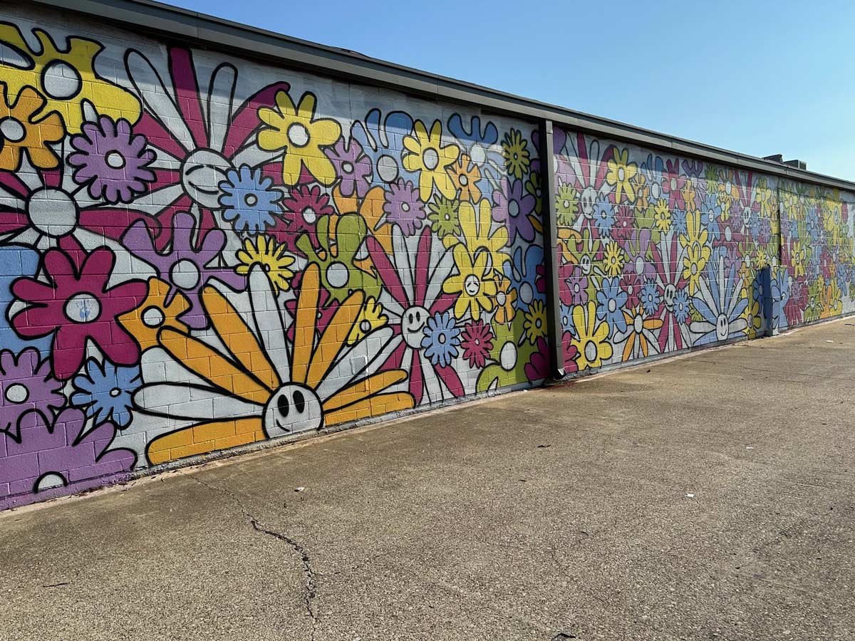 Colorful flower mural on the side of brick building
