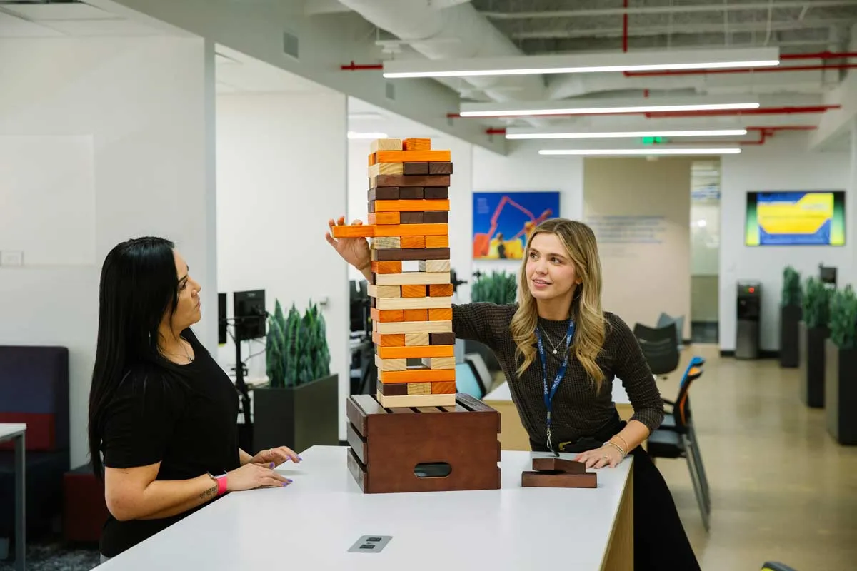 Two women playing giant jenga in office