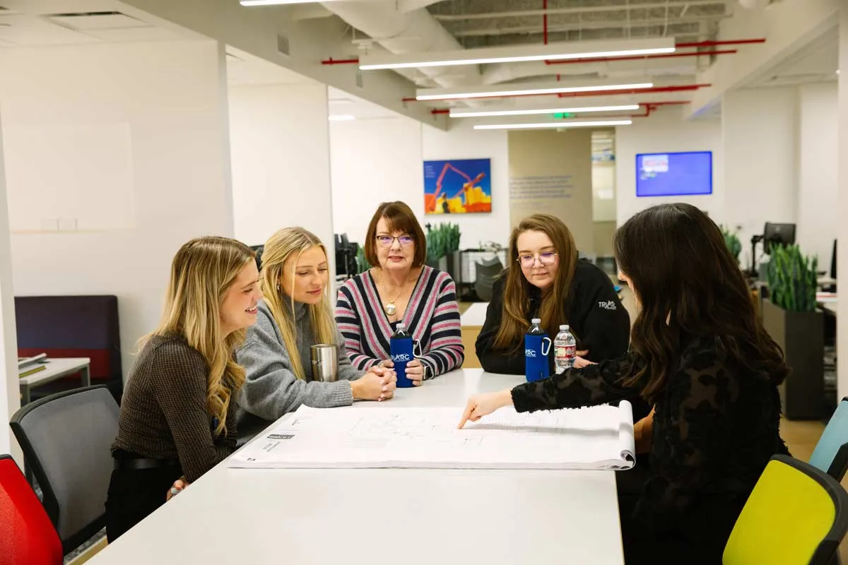 Group of women sitting at table in office review blueprints