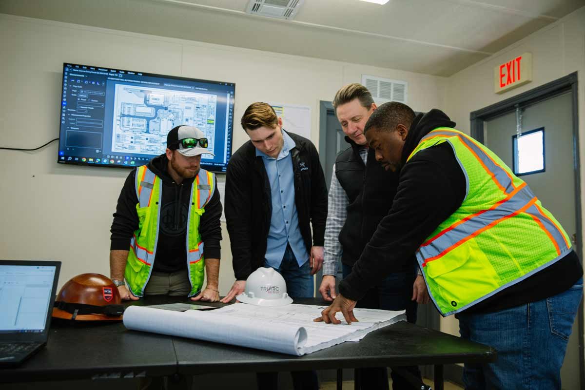 Team of contractors around set of blueprints in office