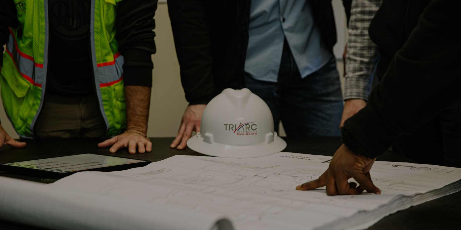 Group of workers looking at blueprints with TriArc hard hat