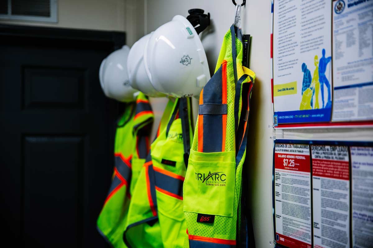 Vests and hardhats hanging on office wall